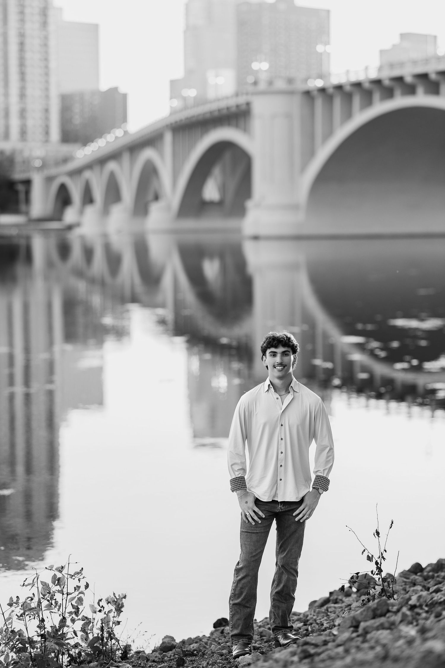 Black and white portrait of someone in a white sweater sitting relaxed on a wooden park bench.