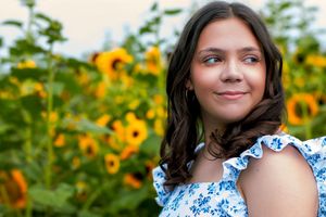 Garden portrait with sunflowers and blue ruffled summer dress.