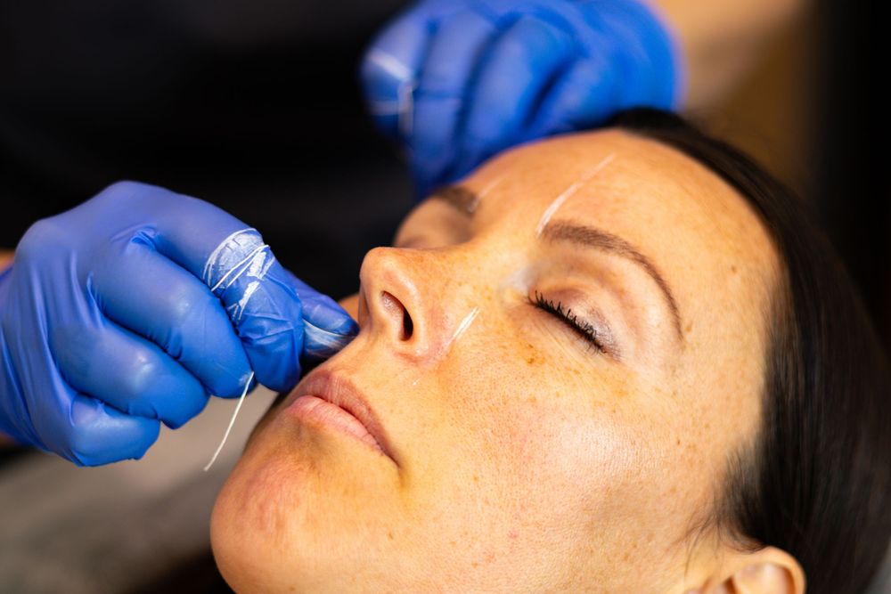 Close-up of an esthetician performing a facial treatment with blue gloves.