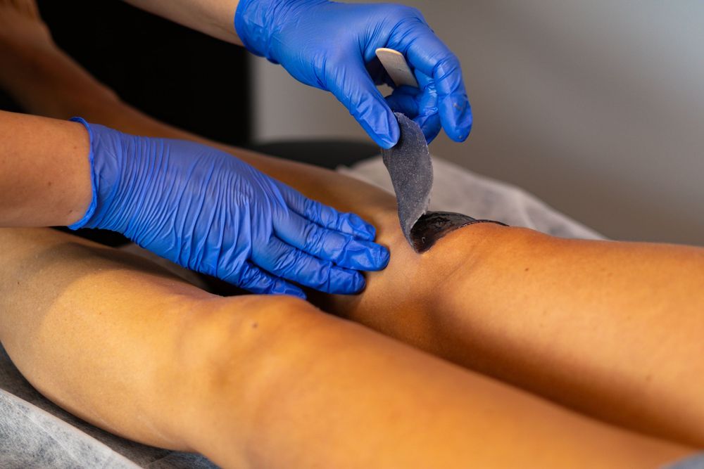 Close-up of professional waxing treatment being performed with blue medical gloves.