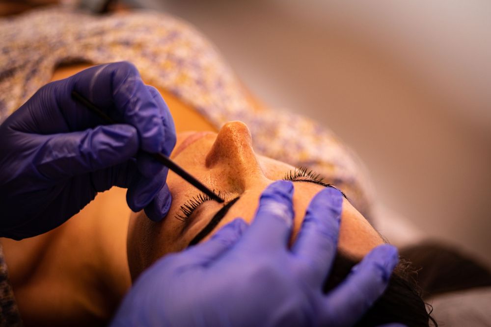 Detailed shot of hands in purple gloves performing precise waxing treatment.