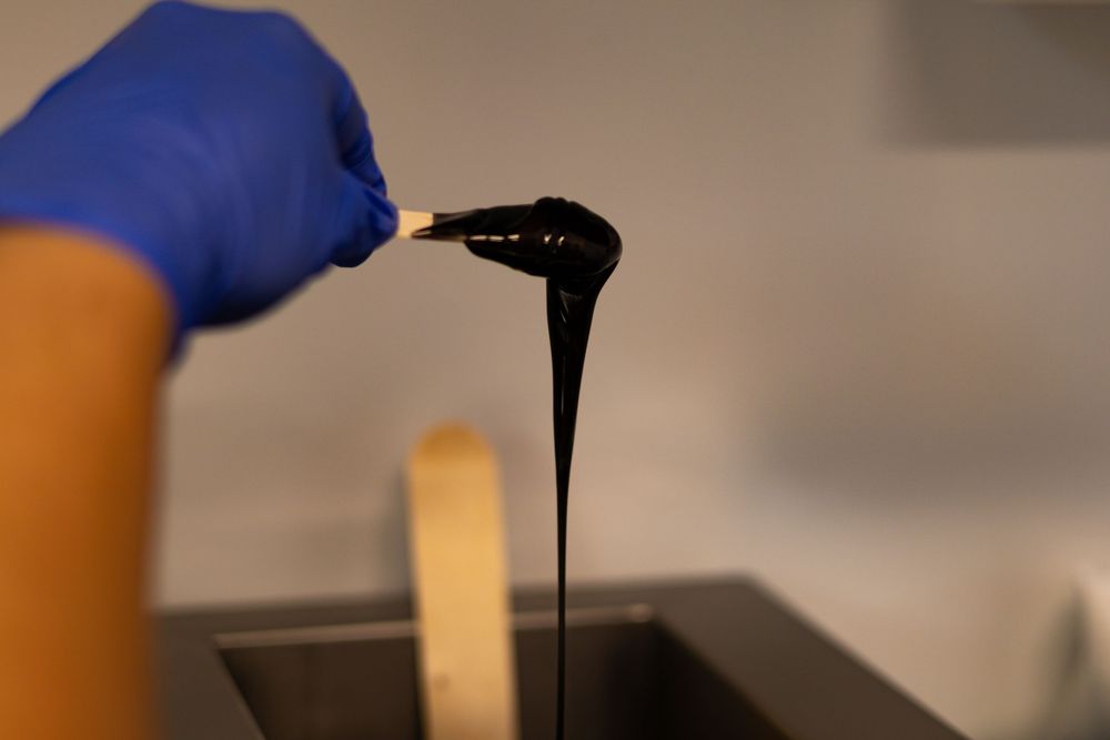 Dark liquid being poured during a cosmetic treatment procedure.