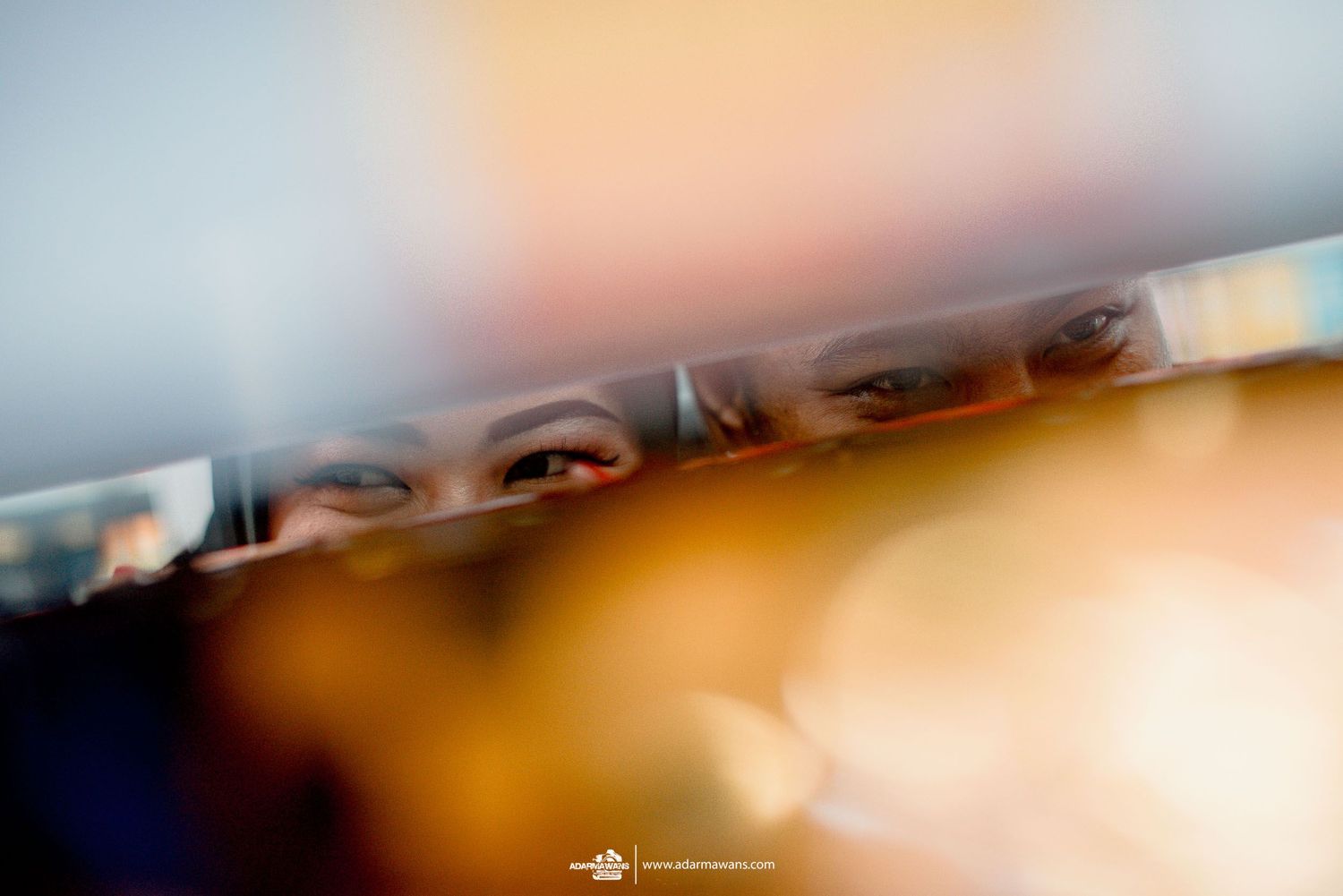 Abstract blurred photography with a narrow focal plane showing fragmented reflective surfaces in warm tones.