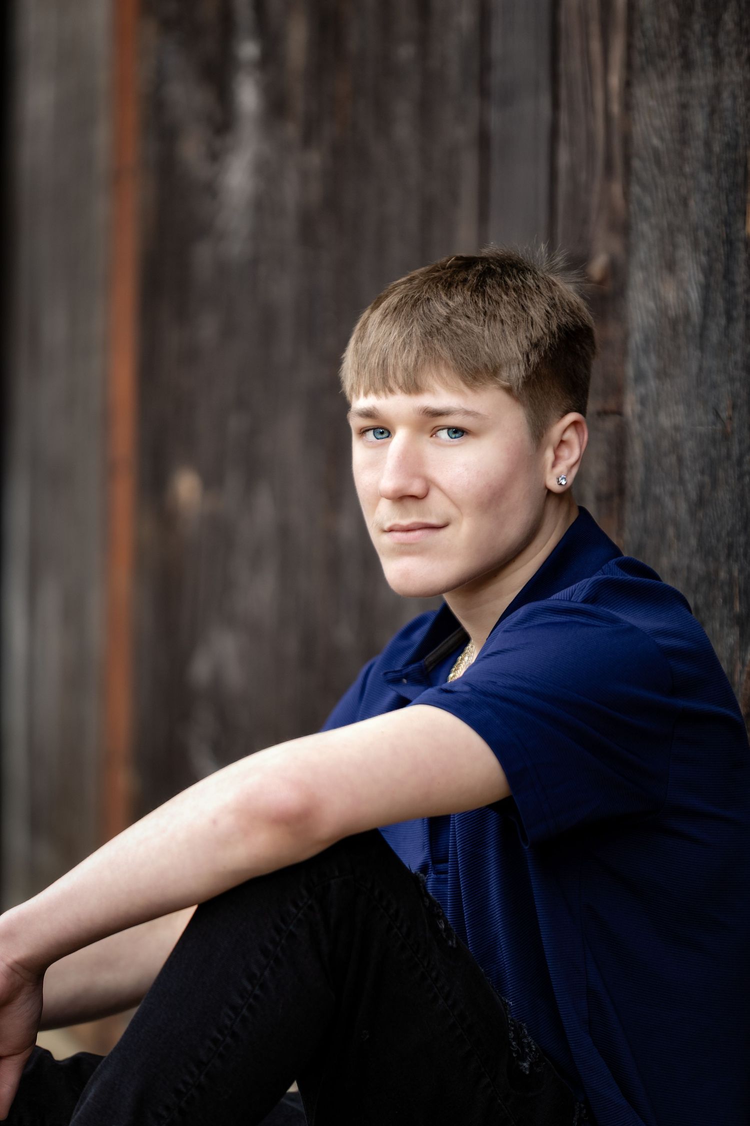Rustic male senior portrait in Lincoln, Alabama, captured against a weathered wooden barn door.