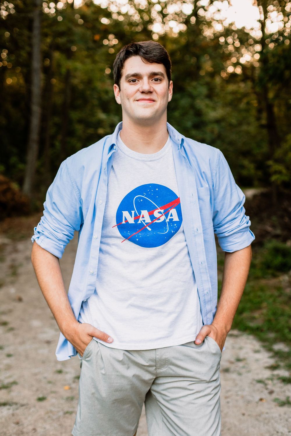 Person wearing NASA t-shirt and light blue button-up shirt in outdoor setting.