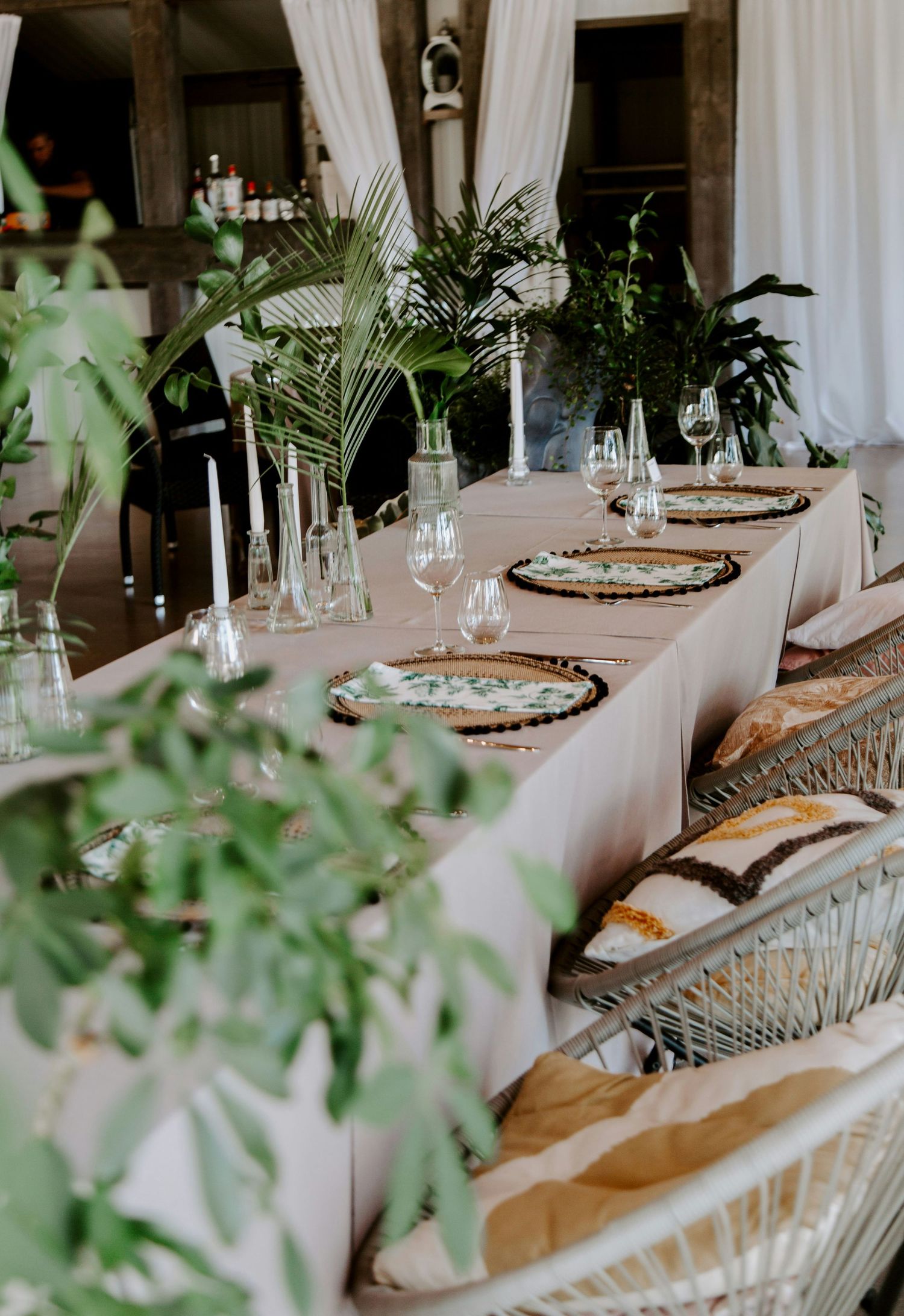 Elegante mesa de recepción de boda con mantelería blanca, cristalería y elementos decorativos naturales.