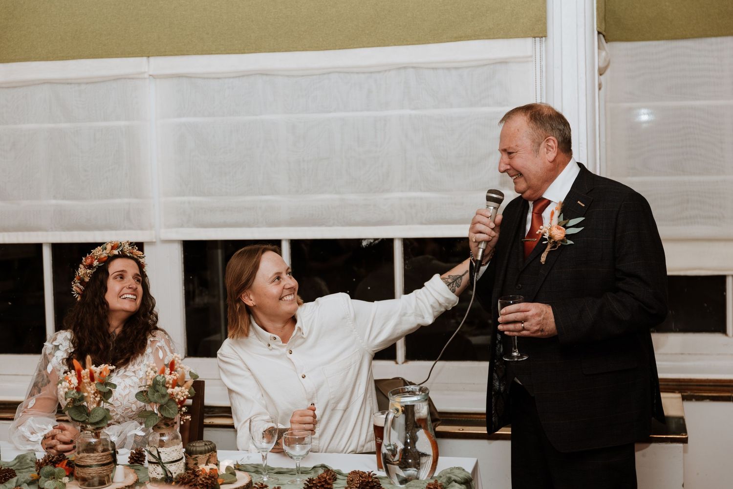 Black and white photo of hands exchanging rings during a wedding ceremony, with visible tattoo on one hand.