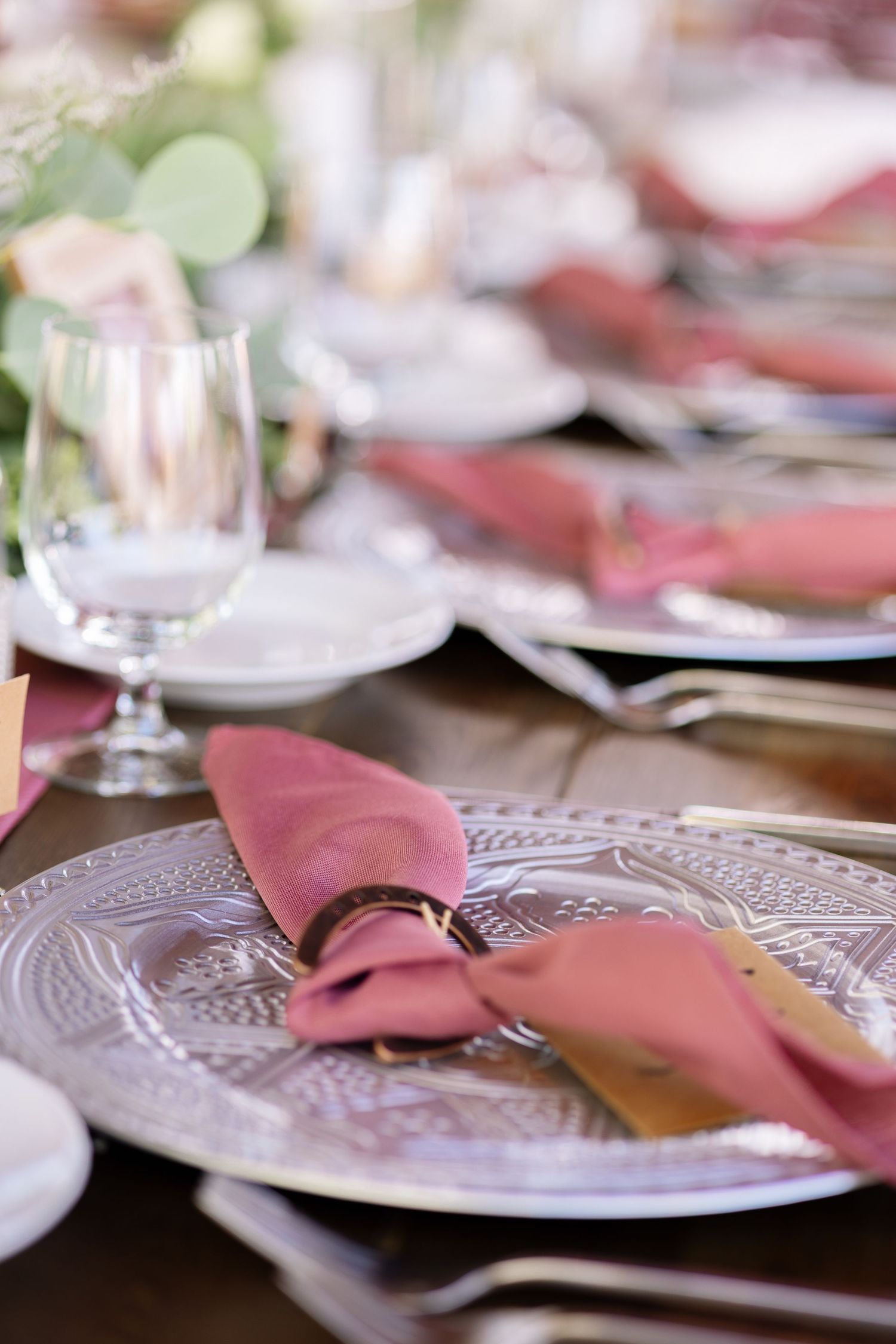 Elegant table setting with pink napkins and decorative plates arranged for a formal dining event.
