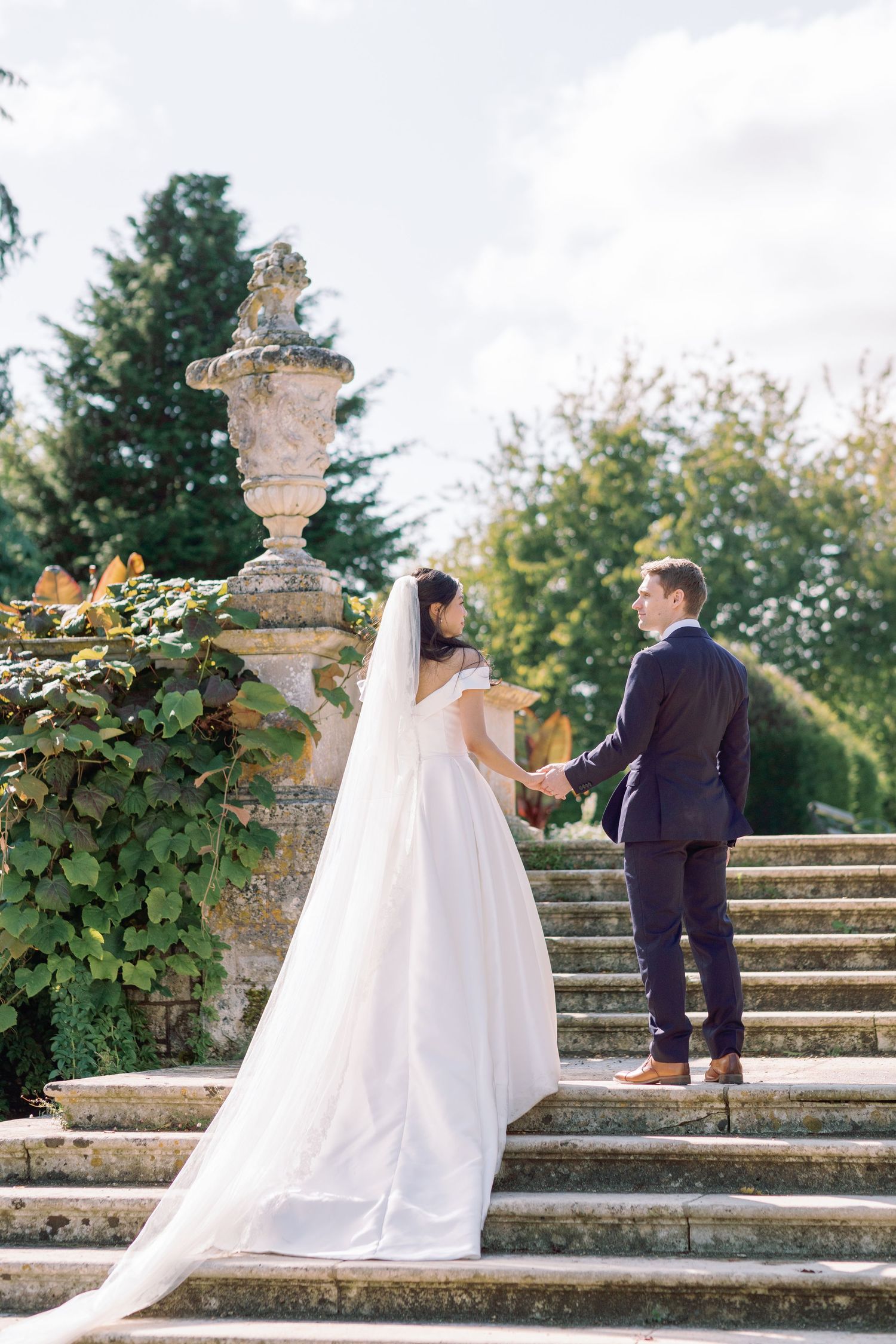 Bride being taken up the stunning stone steps in Kingston Maurward gardens, photographed by Maddie Waters Hampshire wedding photographer