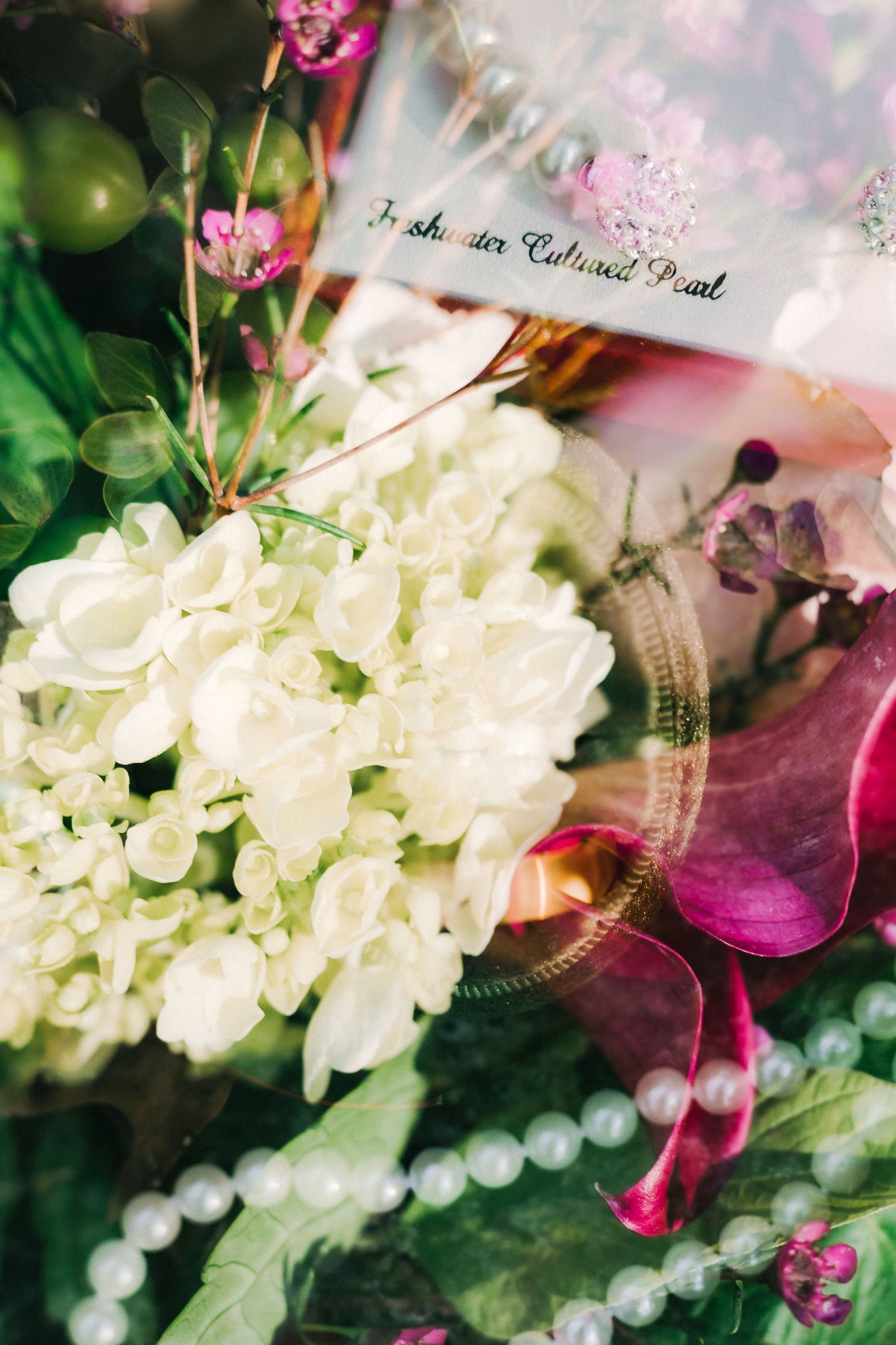 White hydrangea bouquet with pink flowers and pearl accents against a soft dreamy background.