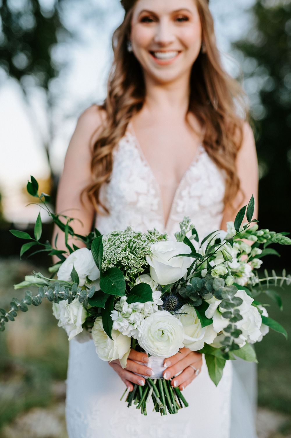 A wedding bouquet of white flowers and lush greenery is held against a white dress in a series of close-up photos.