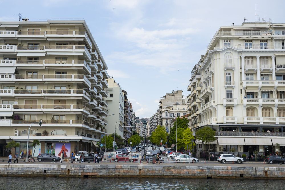 A series of modern apartment buildings with white facades line a street in an urban neighborhood.