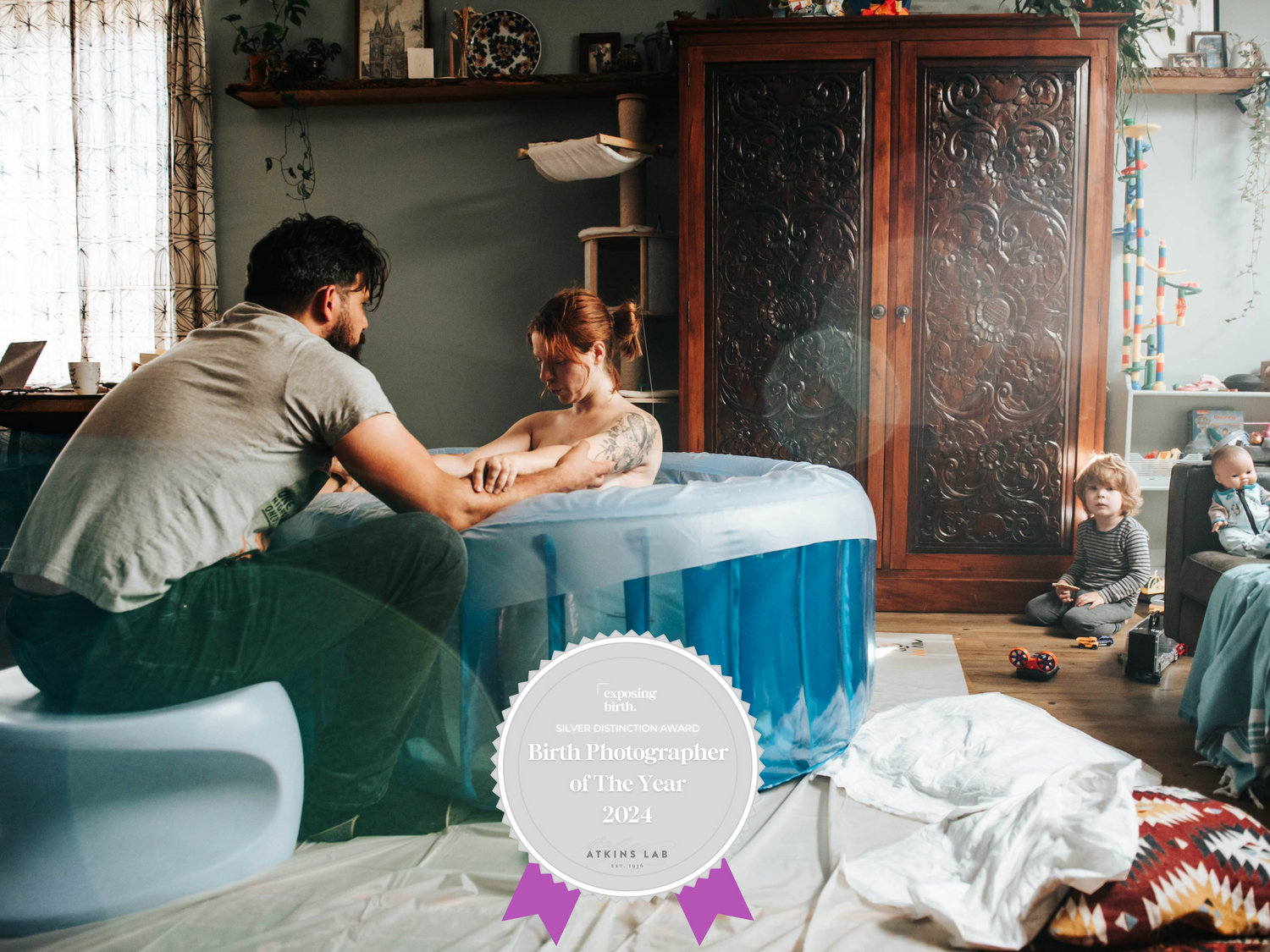 Award-winning birth photography showing a father supporting a woman laboring in a birthing pool.