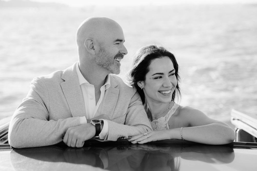 Black and white collage of romantic couple leaning on railing with scenic views in the background.
