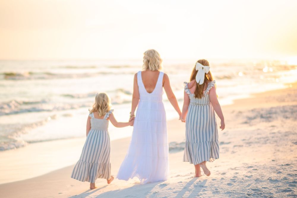 Family walking together on a white sandy beach during golden hour.