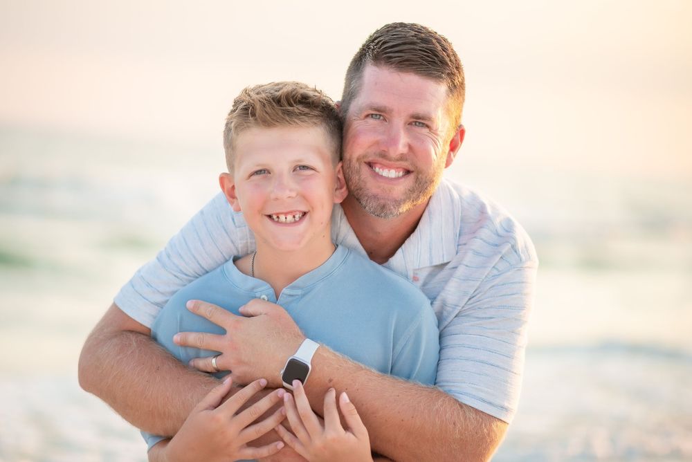 A joyful family moment captured during sunset at the beach with soft golden lighting.