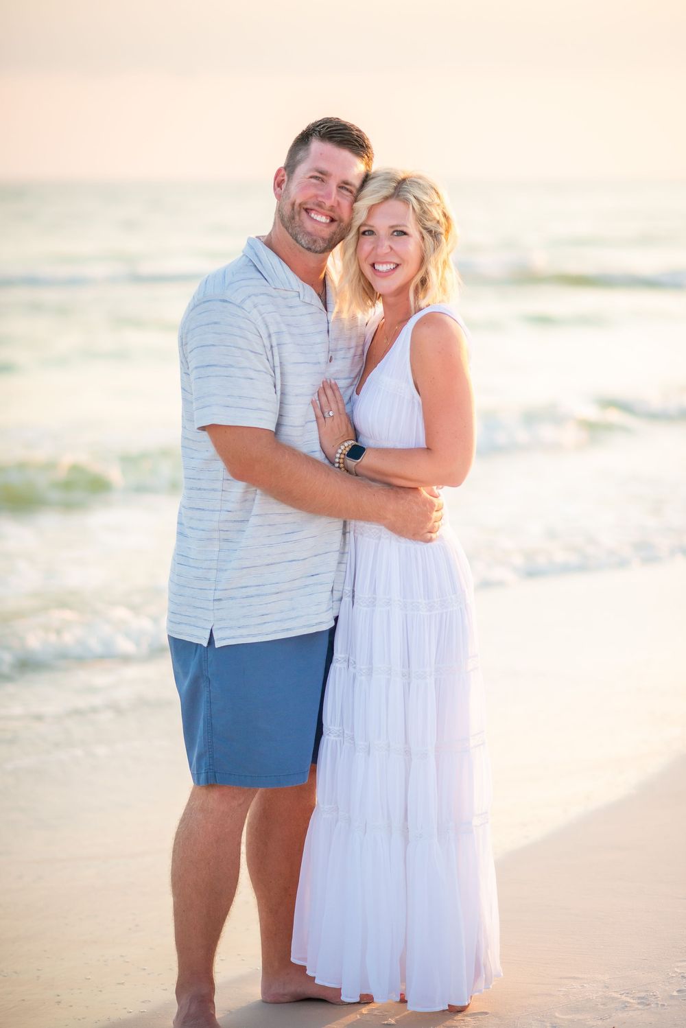 Happy couple sharing joyful moments together during beach photoshoot in matching outfits.