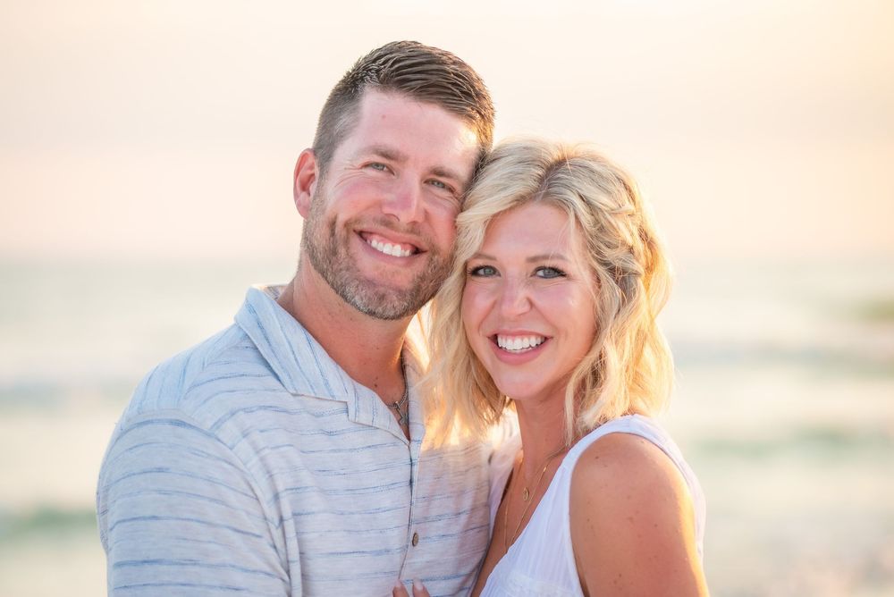 A couple shares a joyful moment together during a sunset beach photoshoot.