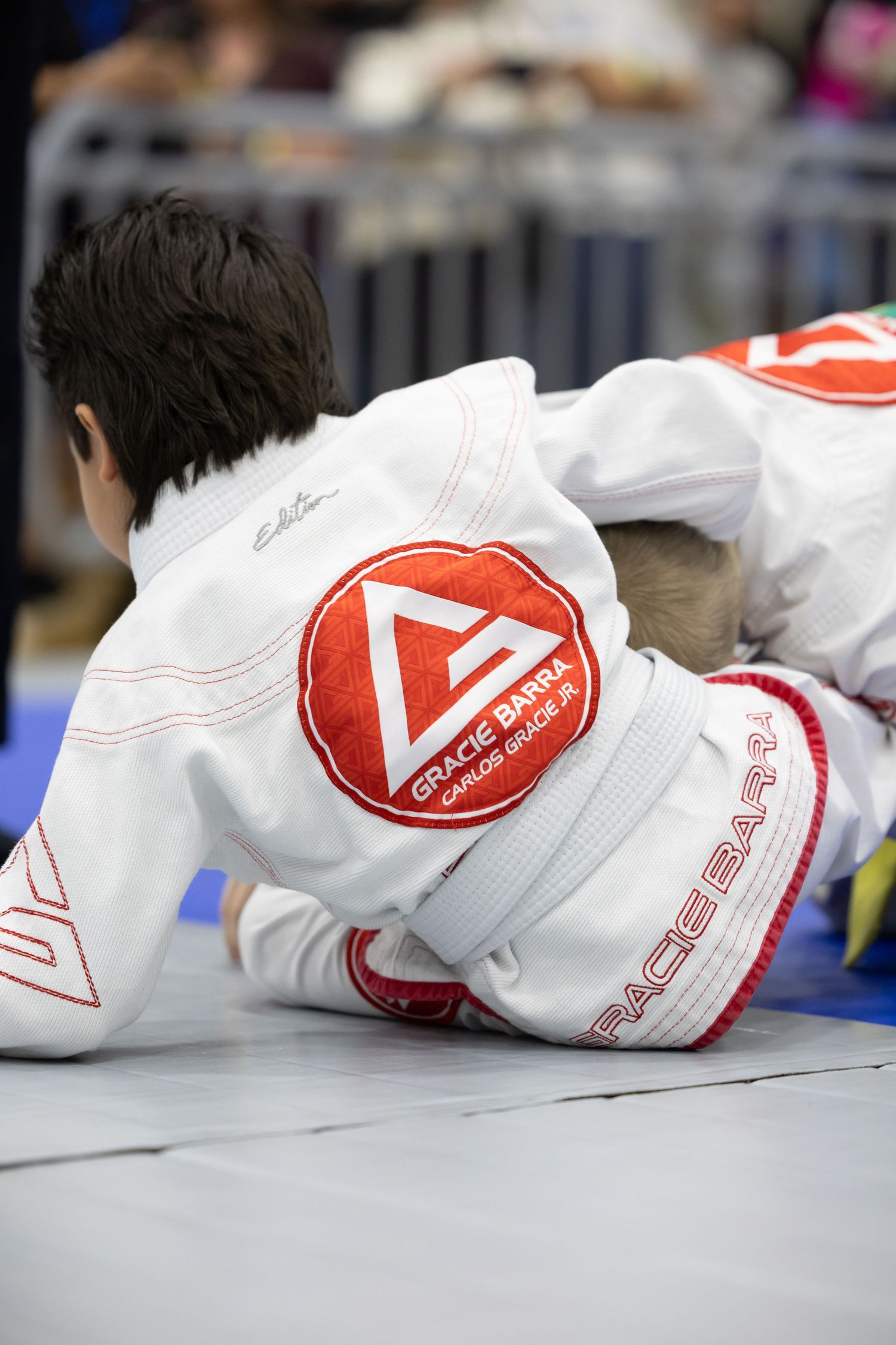 White racing gloves with red logos lying on a light colored surface showing detailed views from different angles.