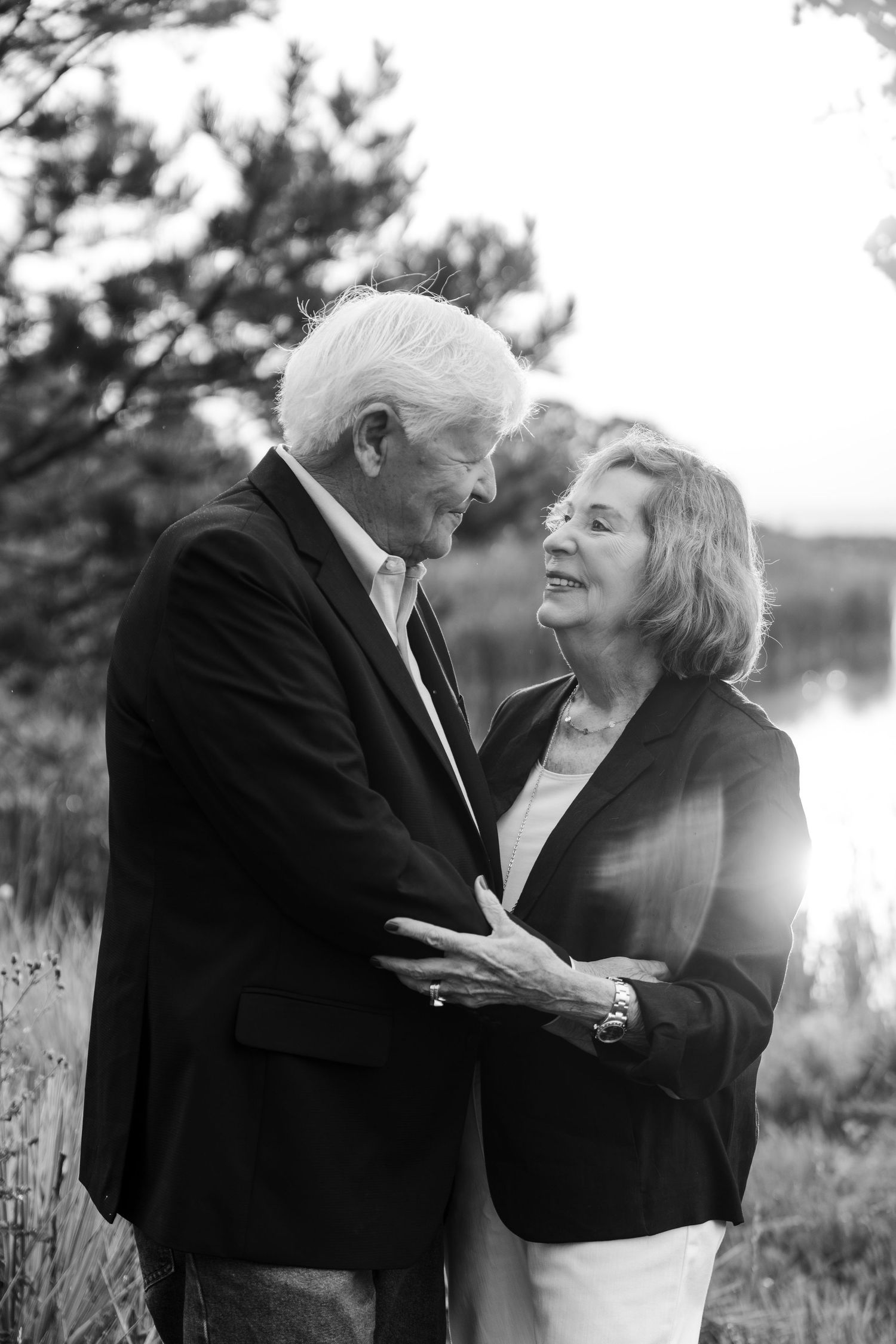 Black and white photo of smiling bride and groom holding hands during outdoor wedding ceremony.