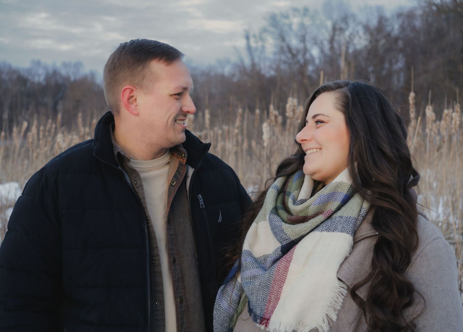 A couple sharing laughter during a winter photo session in a snowy setting.