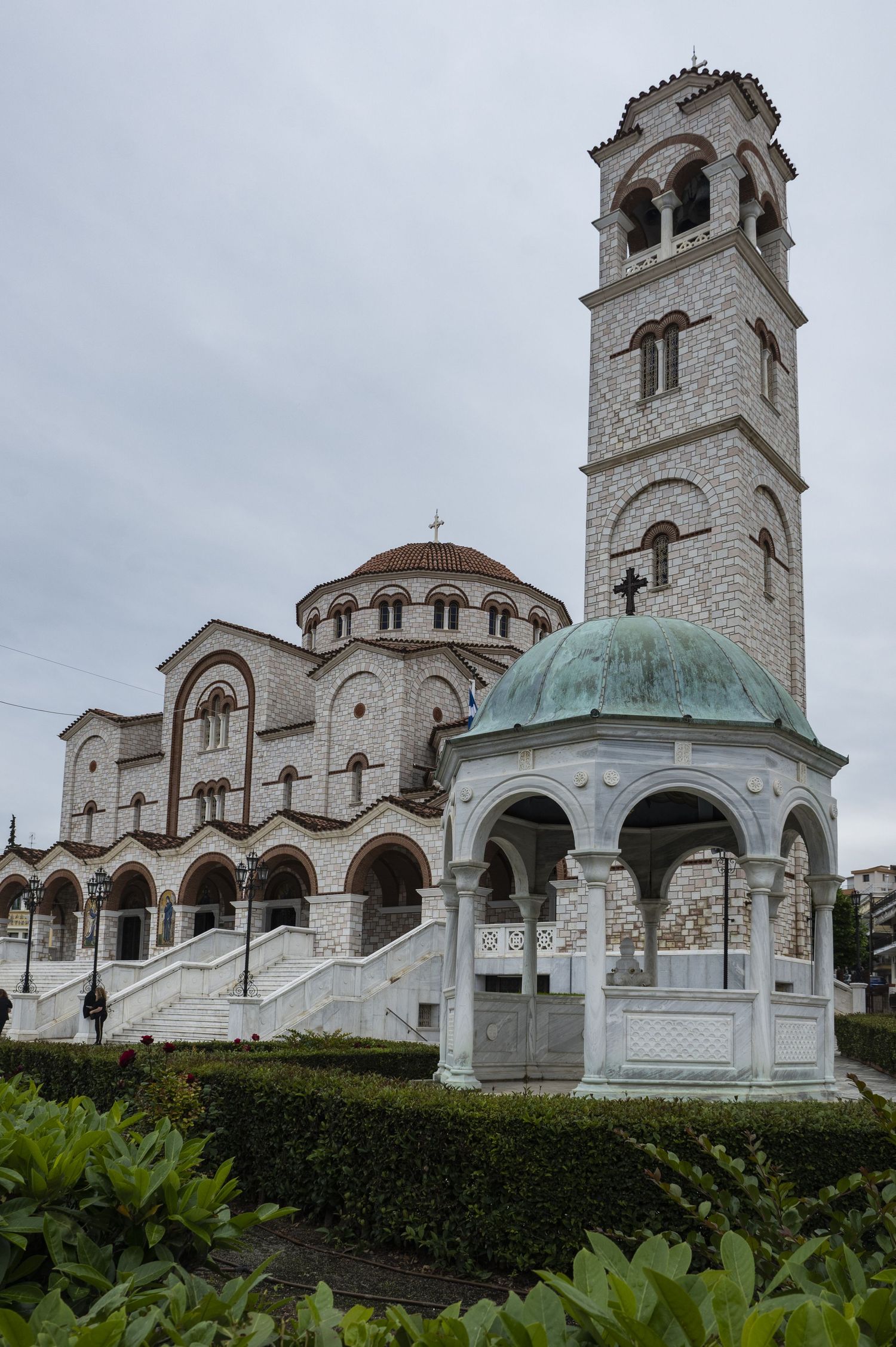 Multiple views of a grand Orthodox church with white stone walls, ornate bell towers, and green domed architecture in Greece.