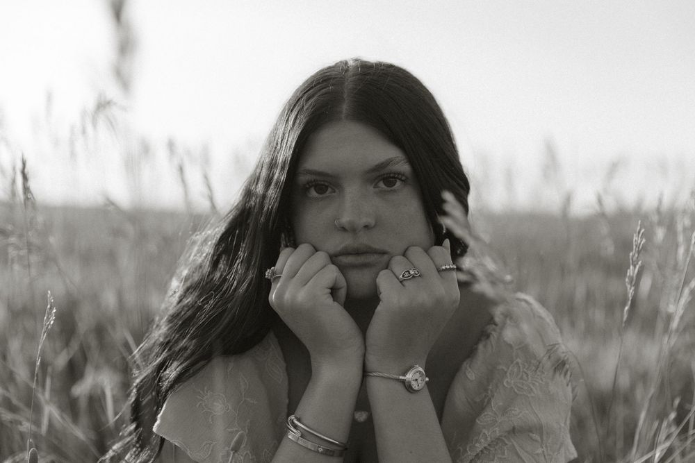 A black and white collage of four photos showing someone in a field with long hair blowing in the wind.