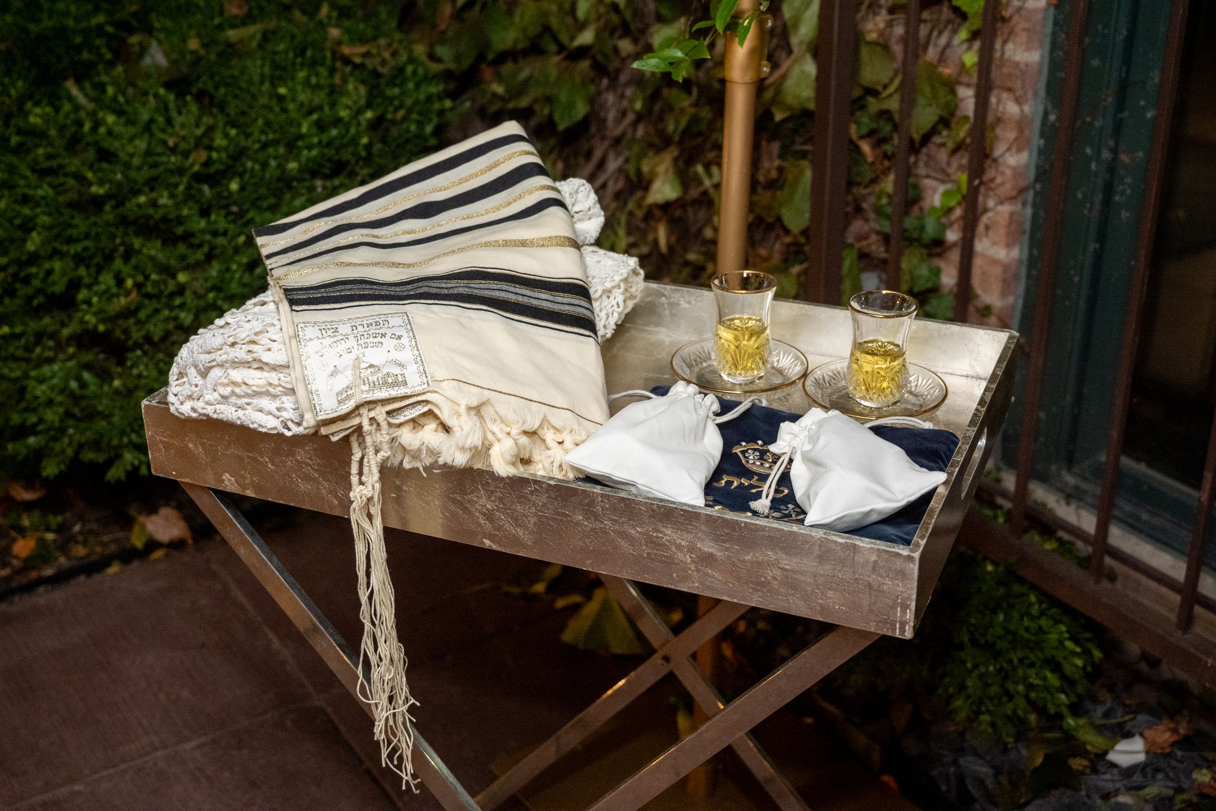 Rustic wooden outdoor table with vintage decor and lace tablecloth set for a garden party or wedding reception.