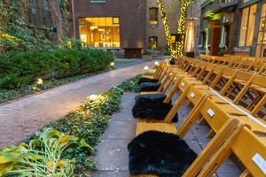 Rustic outdoor wedding venue with wooden benches and string lights creating a warm evening ambiance.