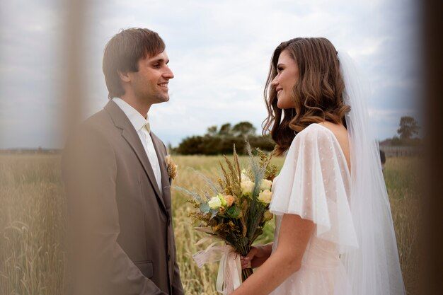A couple in wedding attire share a romantic moment in a sunlit field during golden hour.