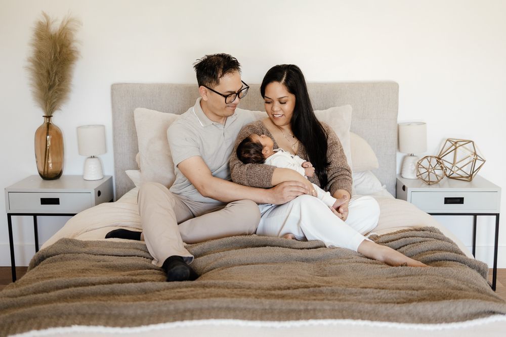 parents cuddle their new baby on their bed in Sunnyvale at their in-home newborn photography session