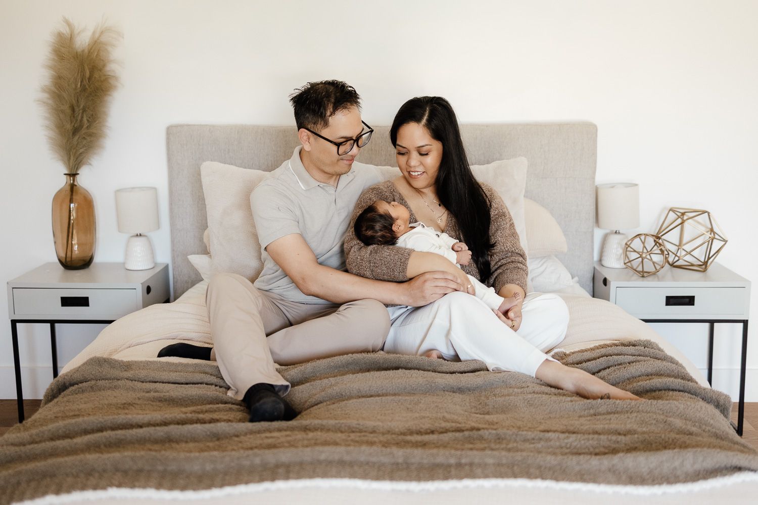 parents cuddle their new baby on their bed in Sunnyvale at their in-home newborn photography session
