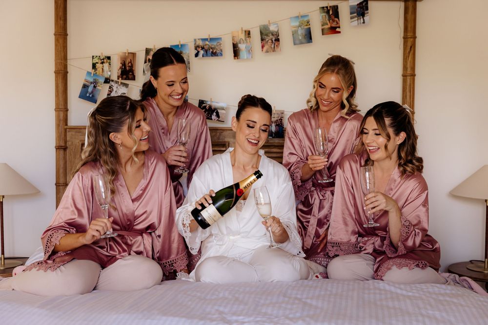 Wedding party in matching pink robes relaxing together during pre-ceremony preparations.