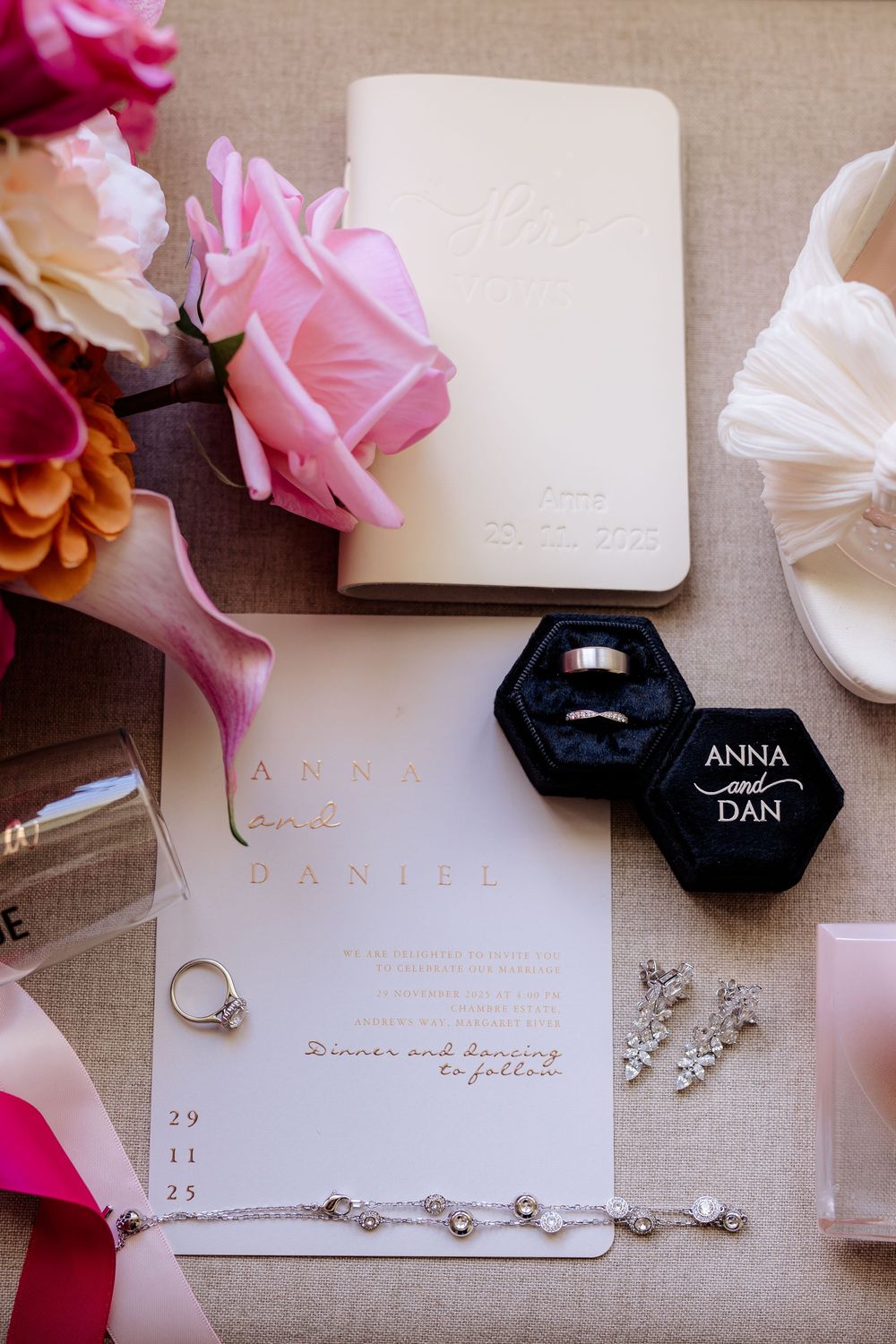 Wedding invitation suite with pink flowers and delicate jewelry details on beige linen background.