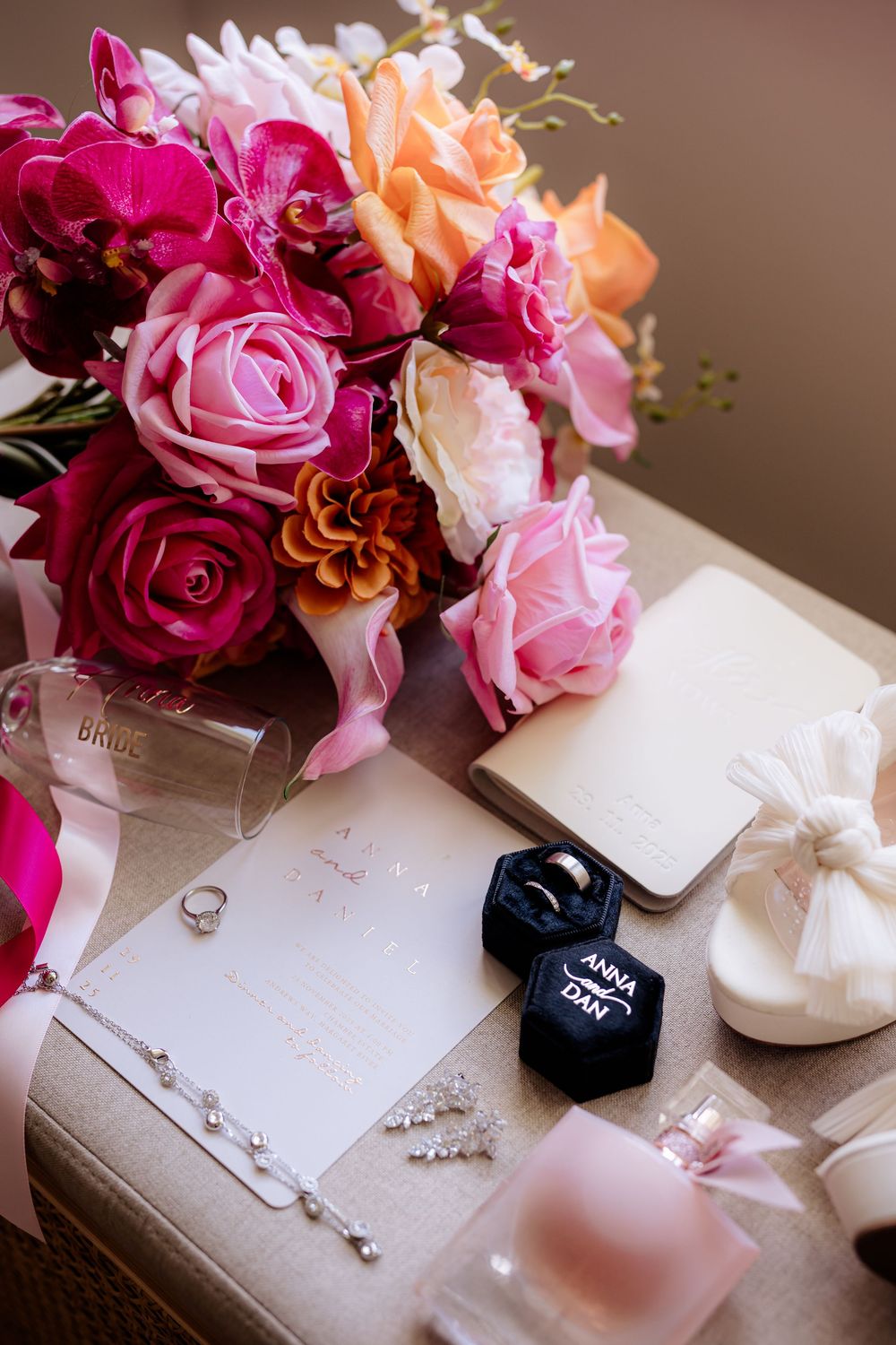 Wedding details including a vibrant pink and peach rose bouquet with rings and accessories on display.
