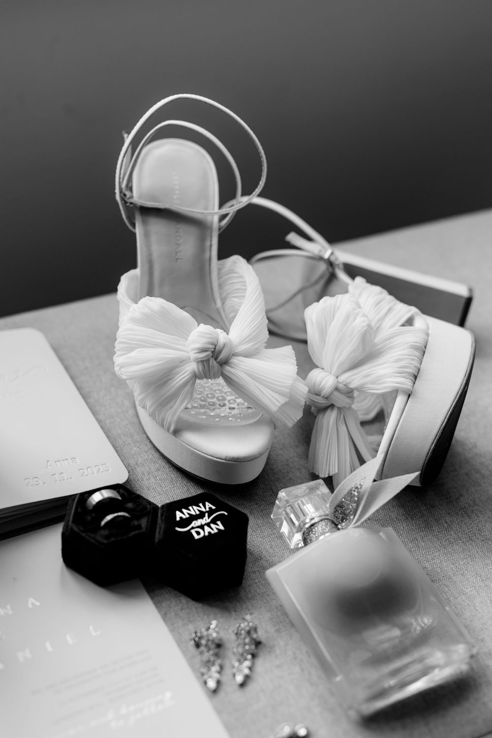White bridal shoes with delicate bows photographed in black and white.