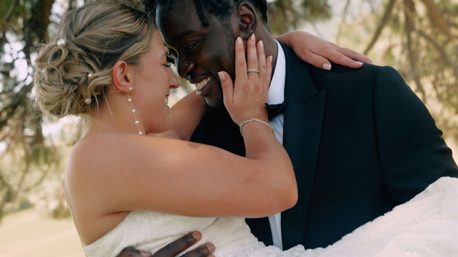 A tender moment between newlyweds as they embrace outdoors in formal wedding attire.