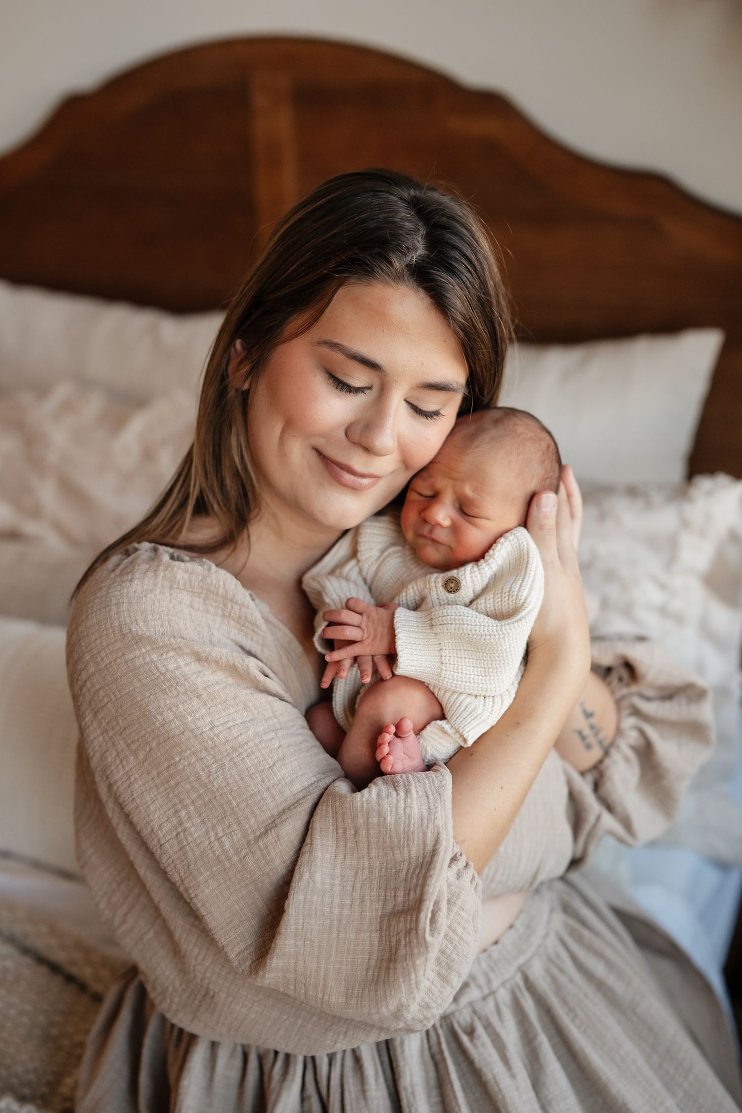 A tender moment captured in warm tones as a mother cradles and bonds with her sleeping newborn baby in soft natural light.