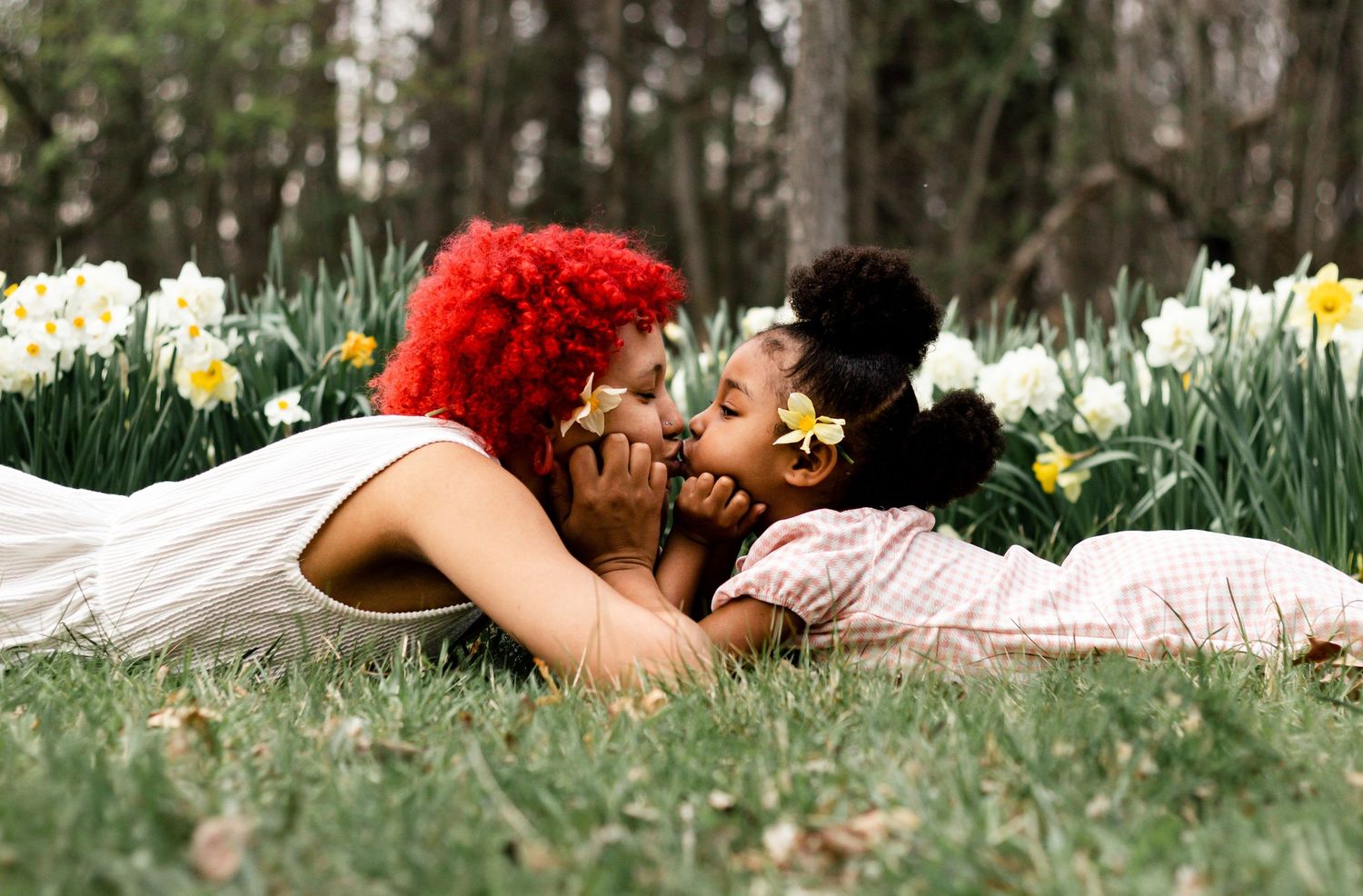 A person lying in a field of white daffodils and red flowers creates a dreamy spring scene.