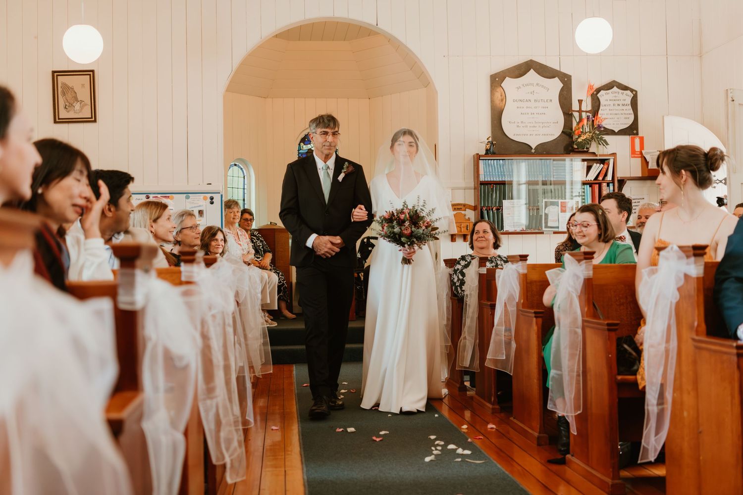 Bride and groom walking down the aisle of a charming white church chapel during their wedding ceremony.