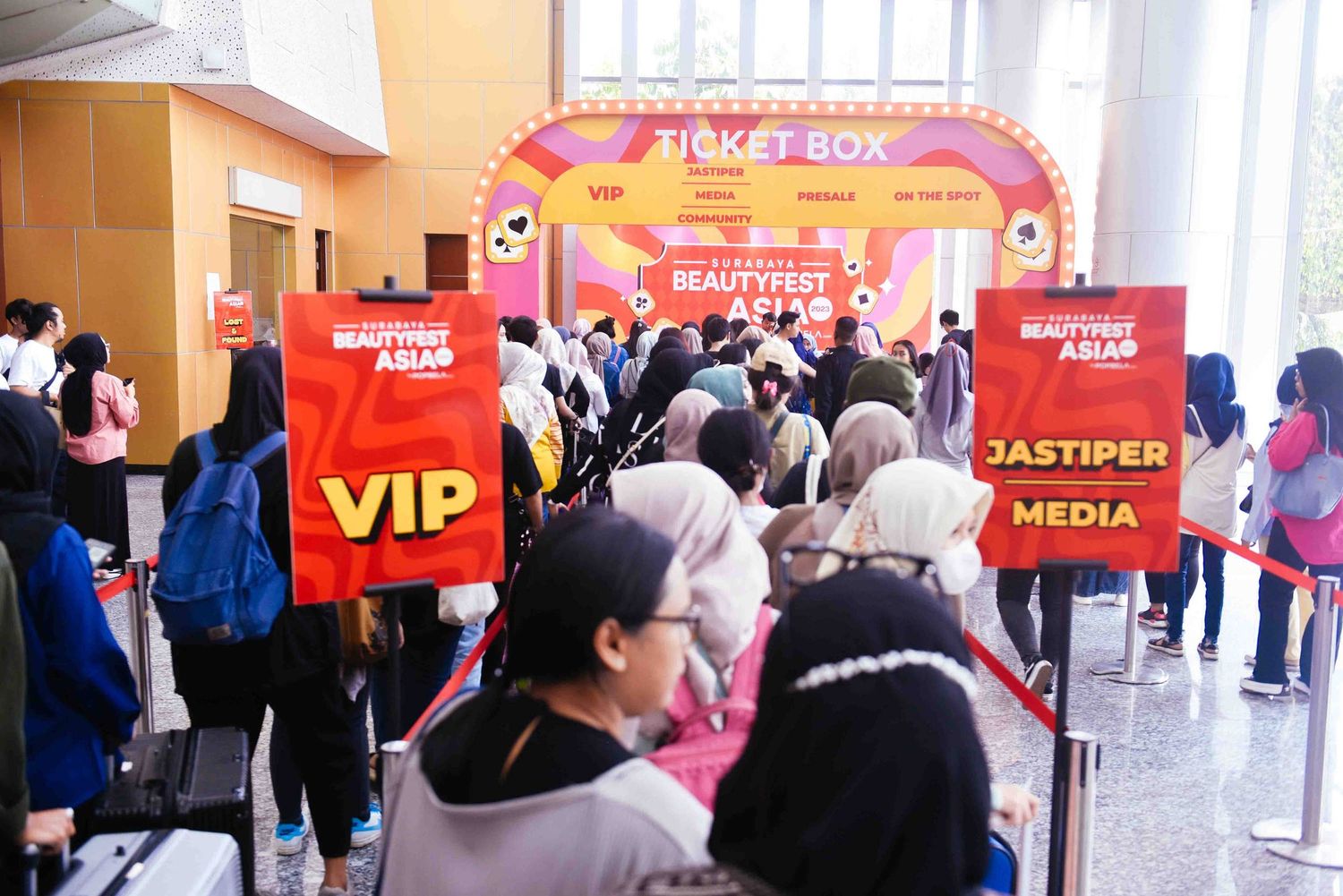 A panoramic view of a crowded indoor event space with red banners and signage displays.