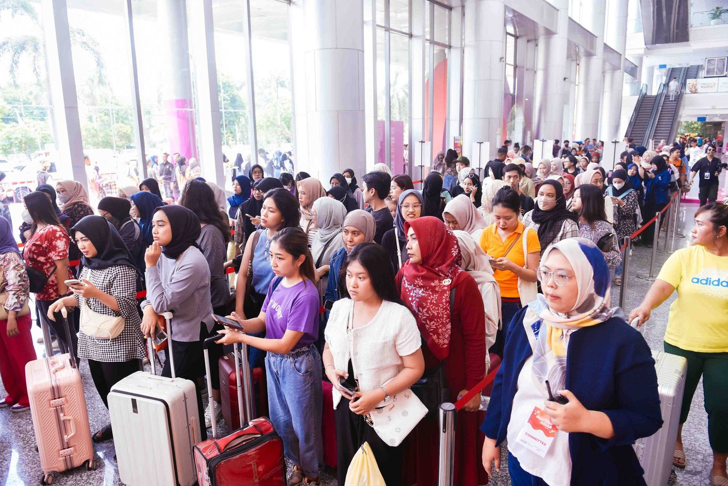 A large crowd of people waiting in line inside a building's covered walkway or corridor.