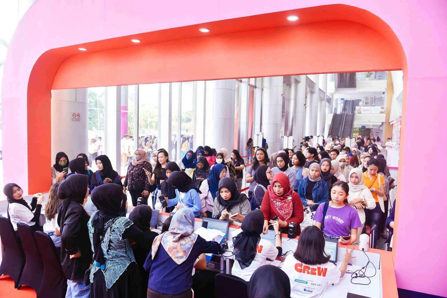 Students gather in a modern pink and orange university hallway for a networking event.