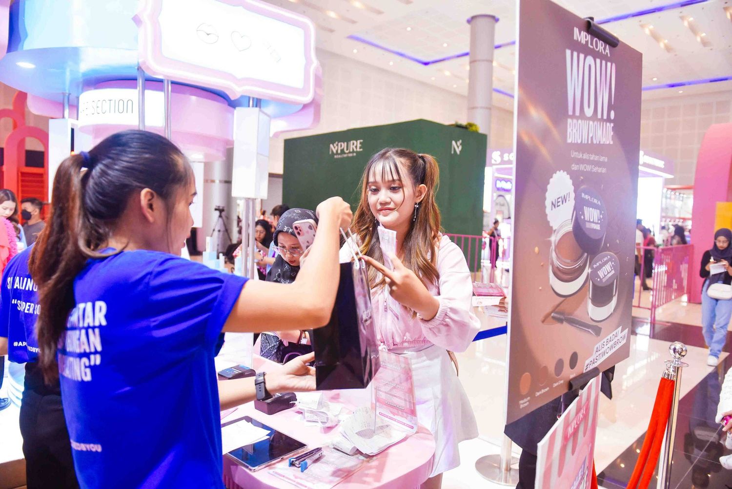 People browse and interact with displays at a beauty product trade show or retail event.