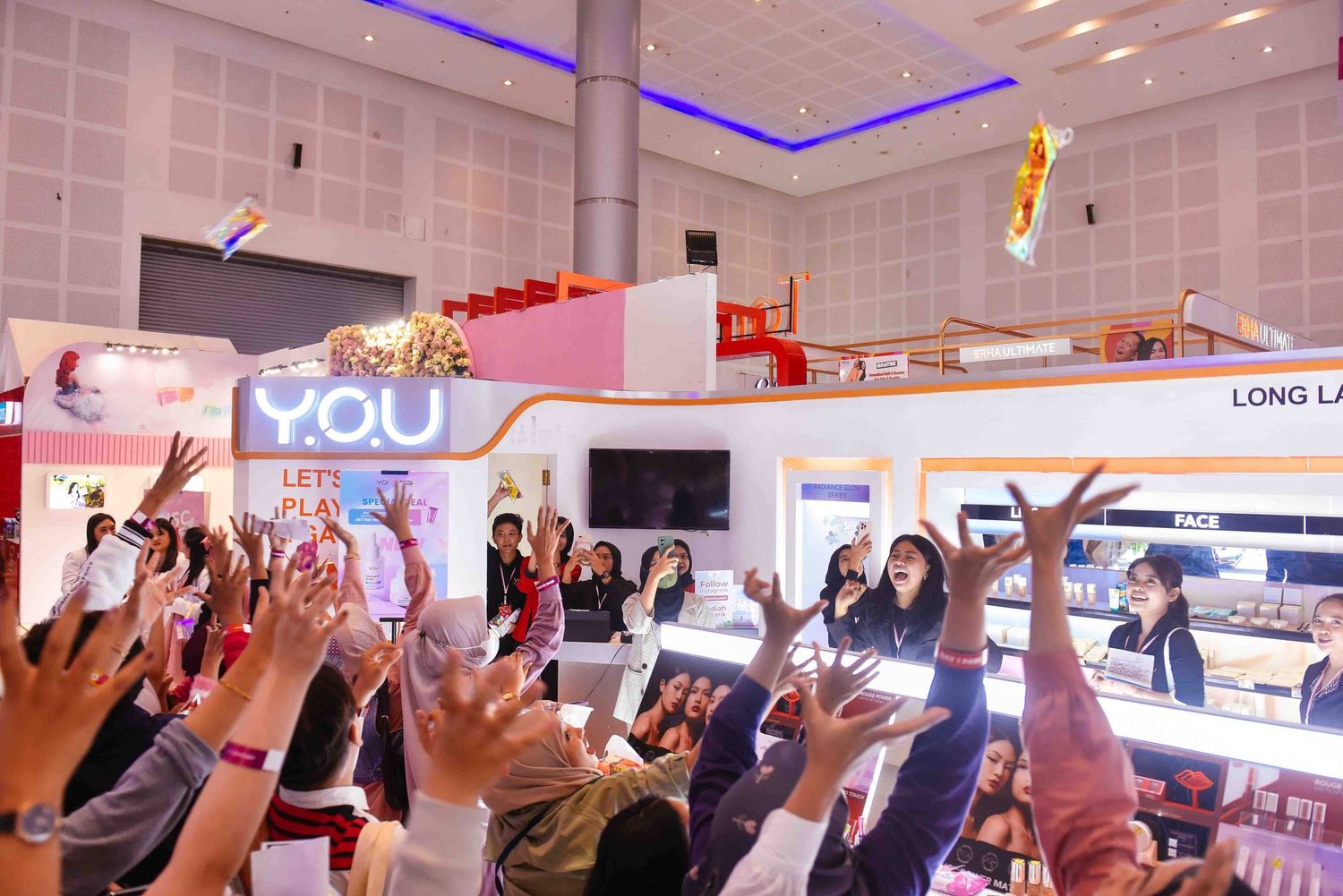 Business conference attendees raise their hands during an interactive presentation session in a modern meeting hall.