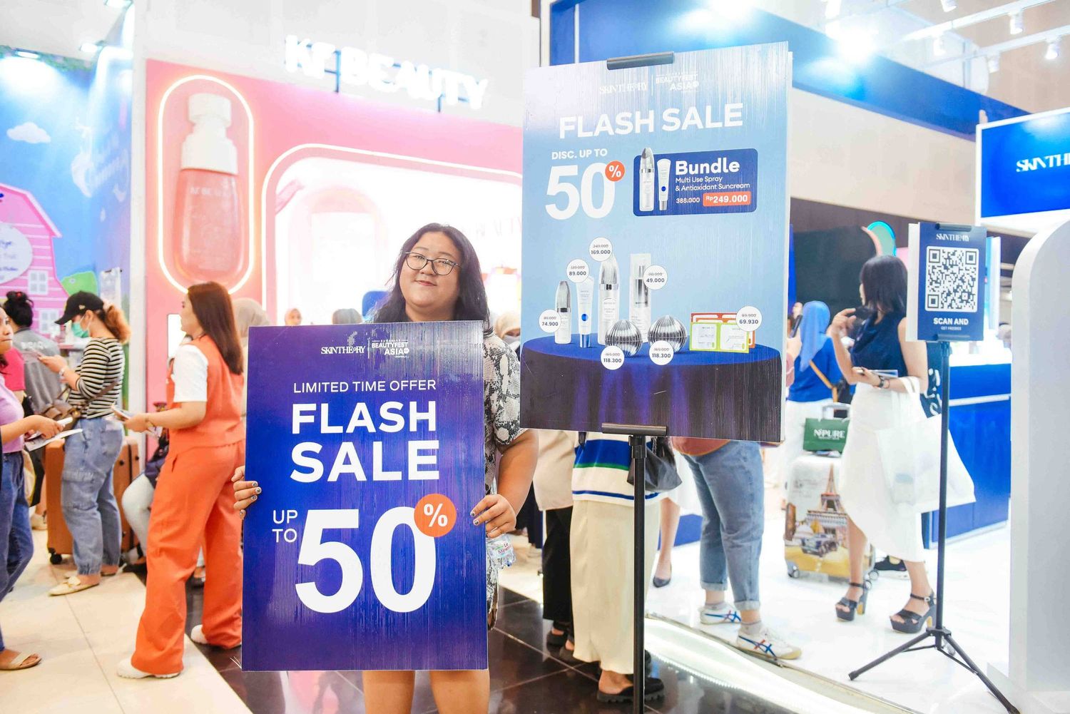 People shopping at a busy retail store with bright blue and pink signage displaying flash sale promotions.