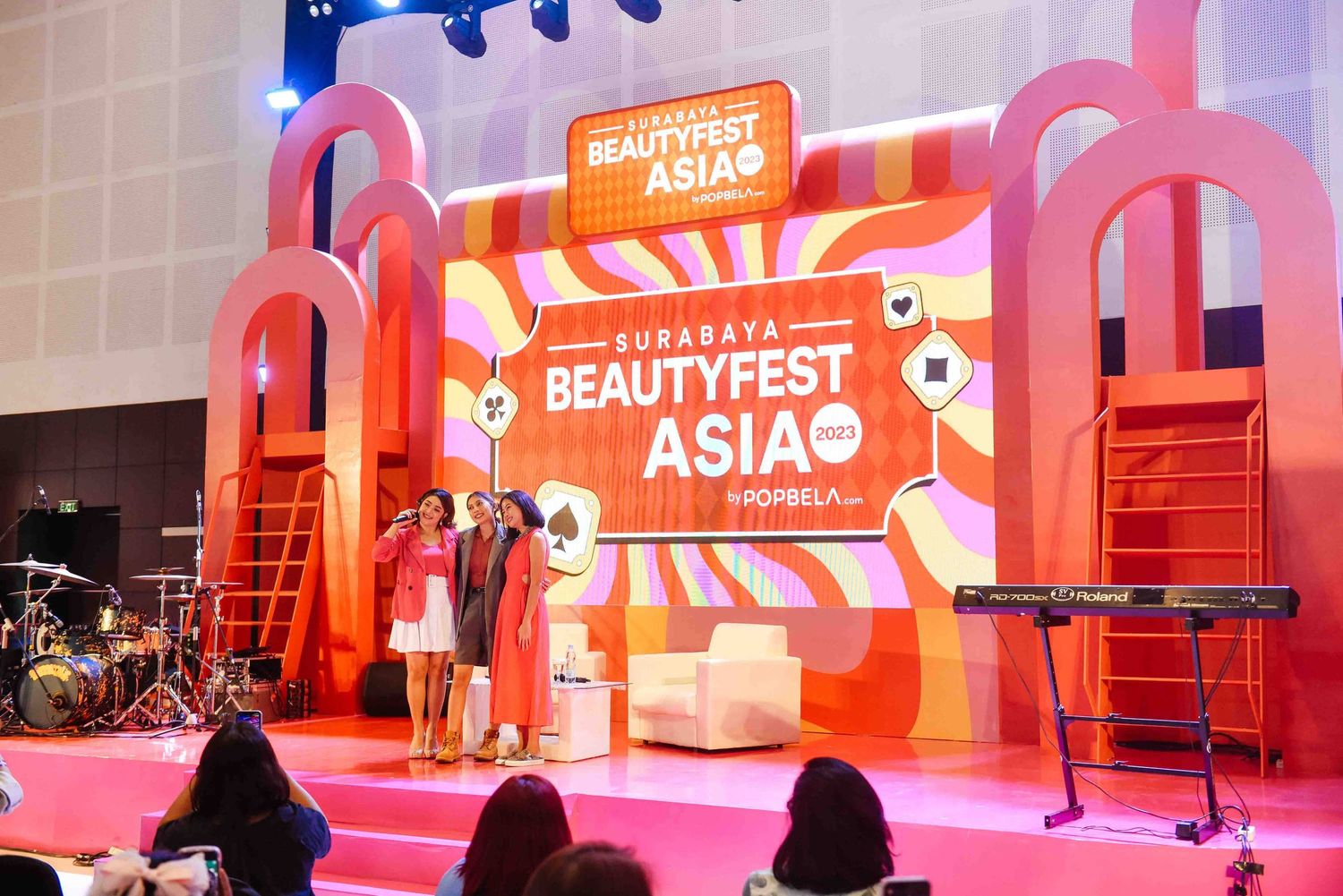 Pink and orange stage setup with 'Beautyfest Asia' signage at a beauty event with audience members seated in front.