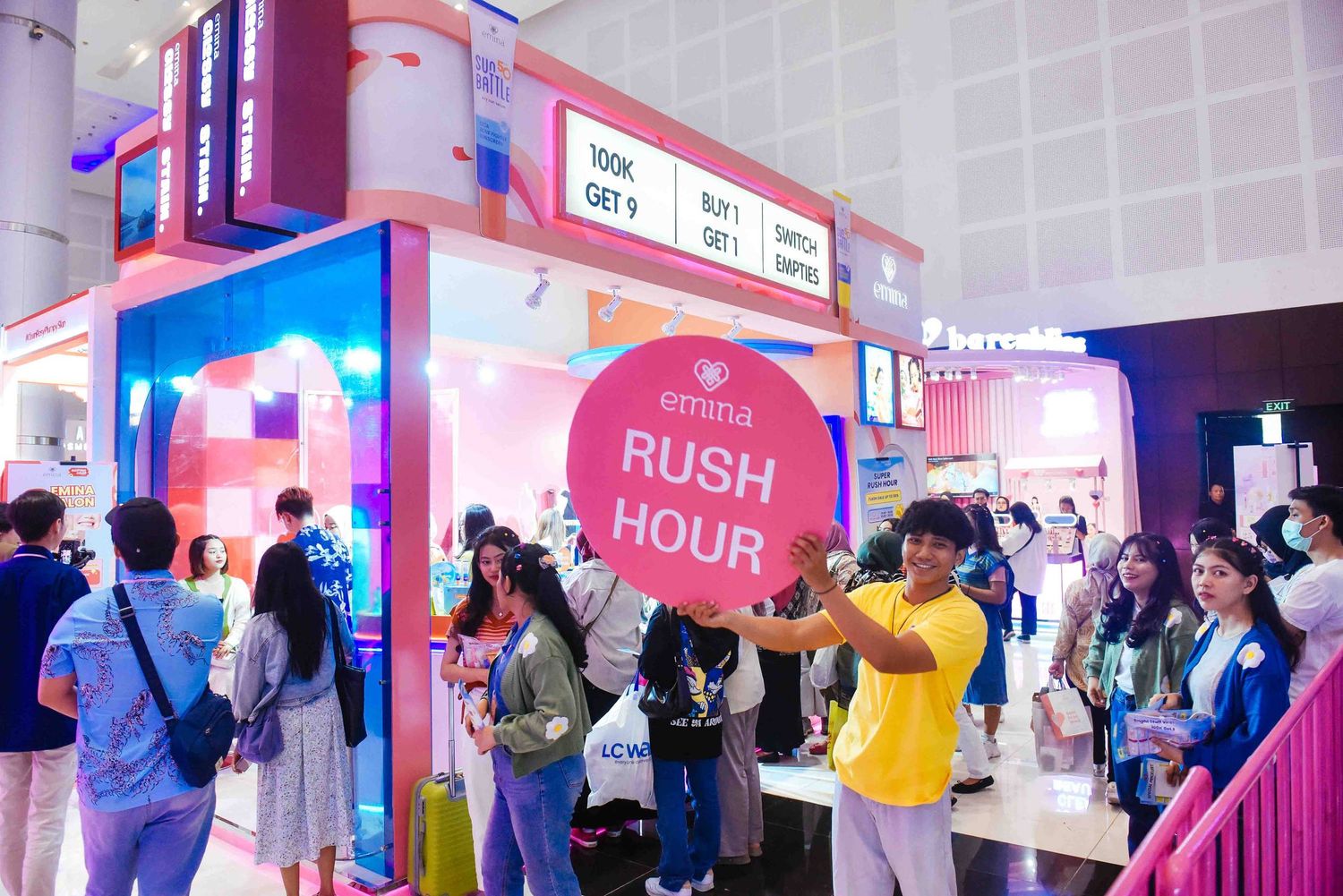 Crowded arcade or entertainment venue with neon lights and digital displays showing colorful signage and games.