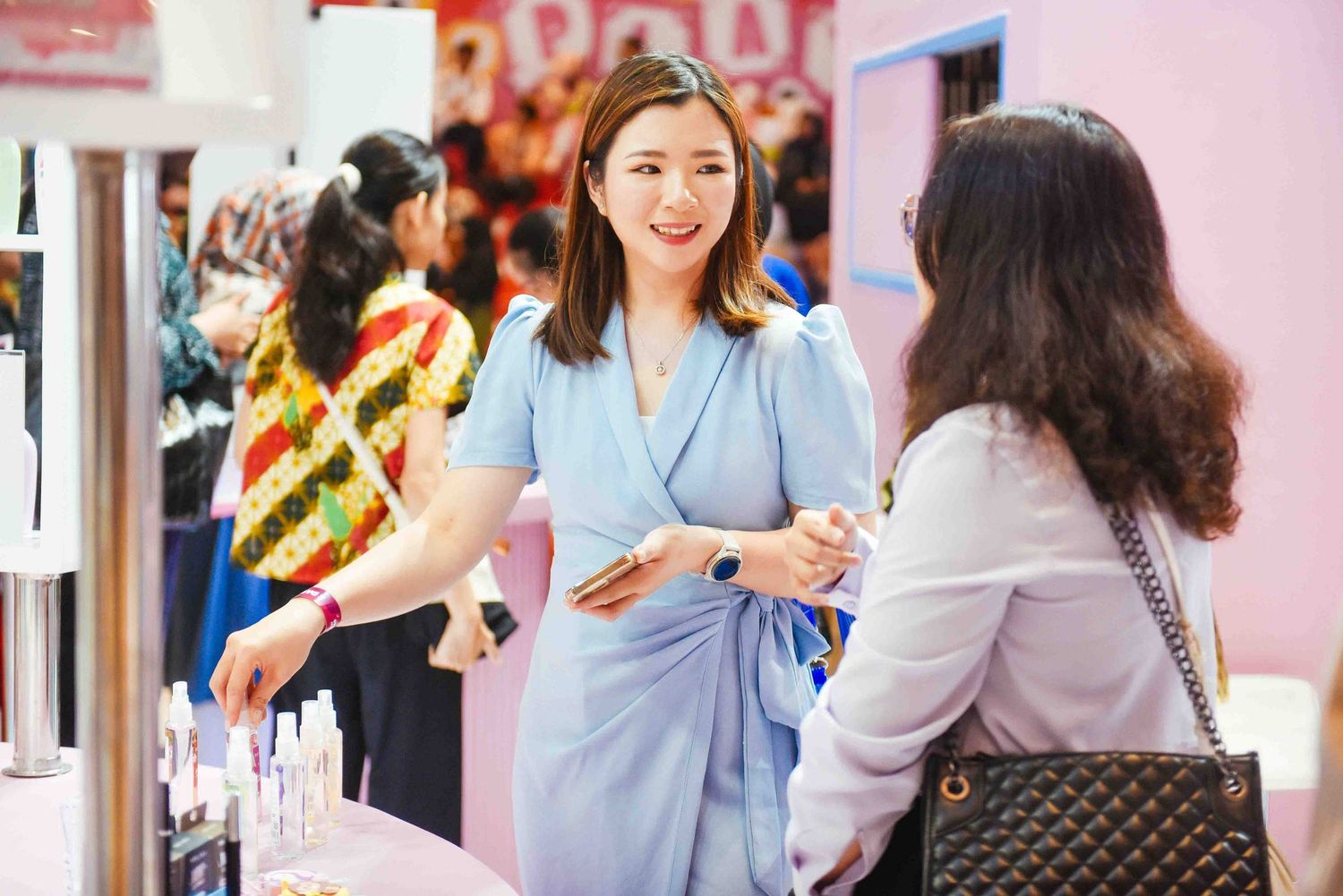 Healthcare workers in blue scrubs interact with patients in a medical facility with pink walls.