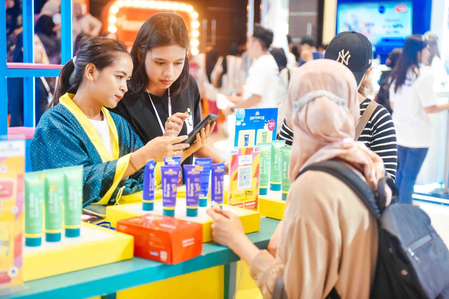 People browse colorful beauty product displays at a cosmetics retail store during a shopping event.